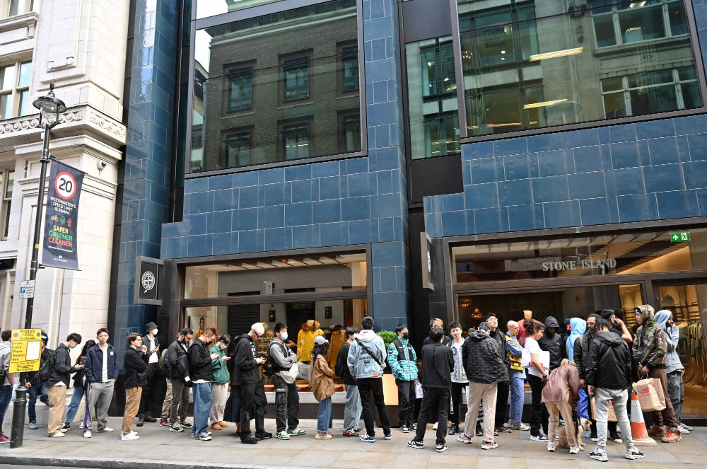 Customers queue to enter a Stone Island shop in London on May 12, 2022. (AFP)