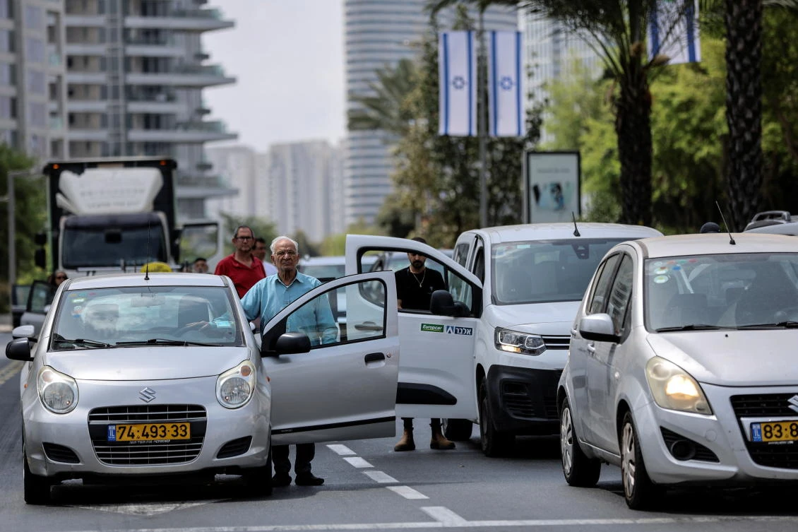 People stand still outside their cars as a two-minute siren marking Israel’s Memorial Day is heard in Tel Aviv on May 4, 2022. (Reuters)