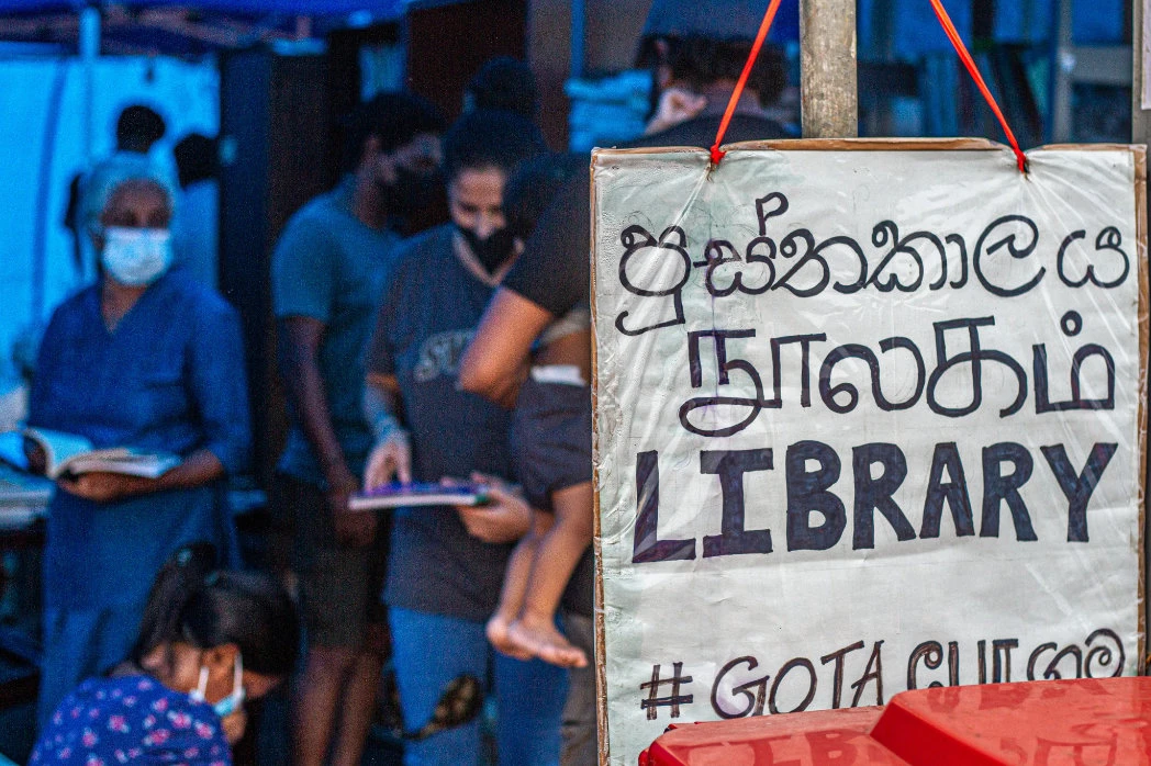 In this photo shared on social media on May 2, people read books at a library set up at the main site of anti-government protests in Colombo. (Photo courtesy: Tilan Weerasinghe)