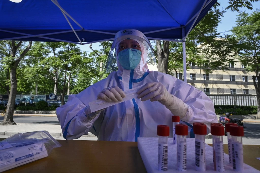 A health worker waits for people to be tested for Covid-19 coronavirus at a makeshift testing site outside a museum along a street in Beijing on May 4, 2022. (AFP)