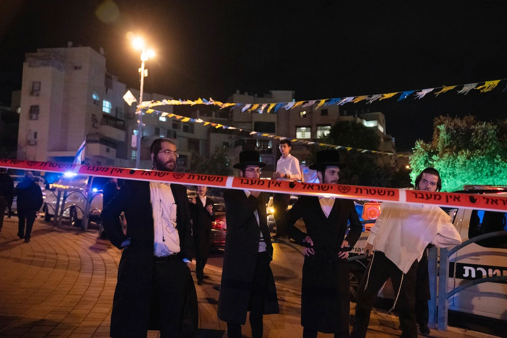 Ultra-Orthodox Jews stand behind police tape after a stabbing attack in the town of Elad, Israel, Thursday, May 5, 2022. (AP)