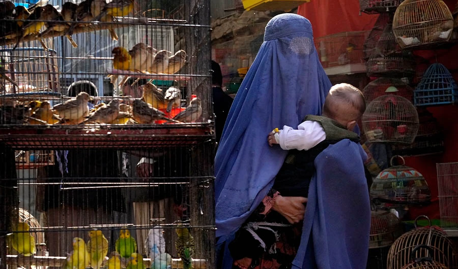 A woman wearing a burka walks through a bird market as she holds her child, in downtown Kabul, Afghanistan, May 8, 2022. (AP)