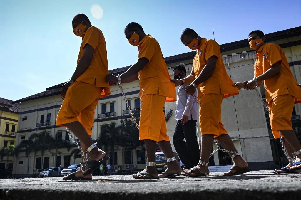 Above, Indonesian police escort suspected drug smugglers from an international drug network on March 29, 2022. (AFP)