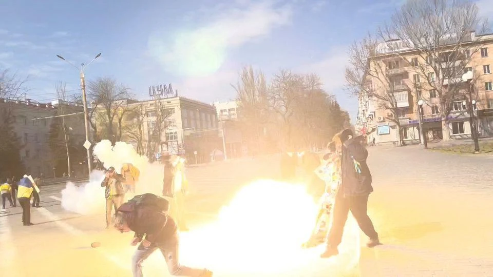 Demonstrators react to stun grenades thrown by Russian troops as they protest the Russian invasion, along Ushakova Avenue in Kherson, Ukraine, Mar. 21, 2022. (Reuters)
