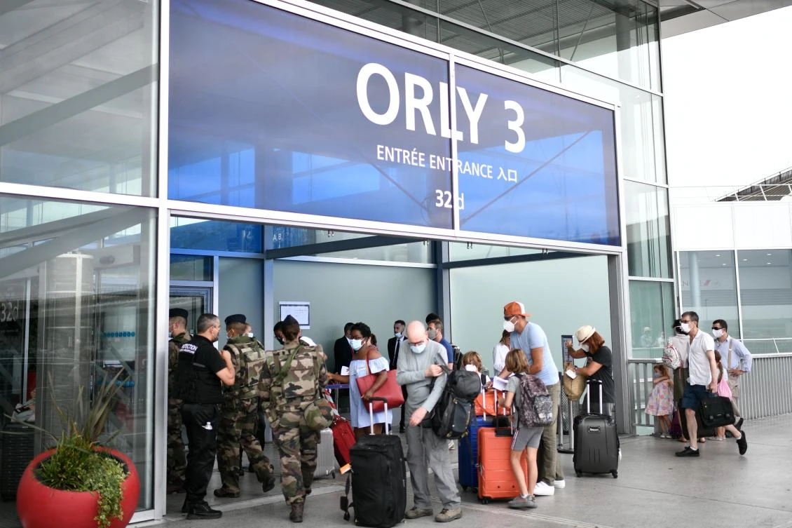 A file photo taken in August 2020 of travelers, wearing protective face masks, line up at the Orly Airport during a major weekend of the French summer holidays. (AFP)