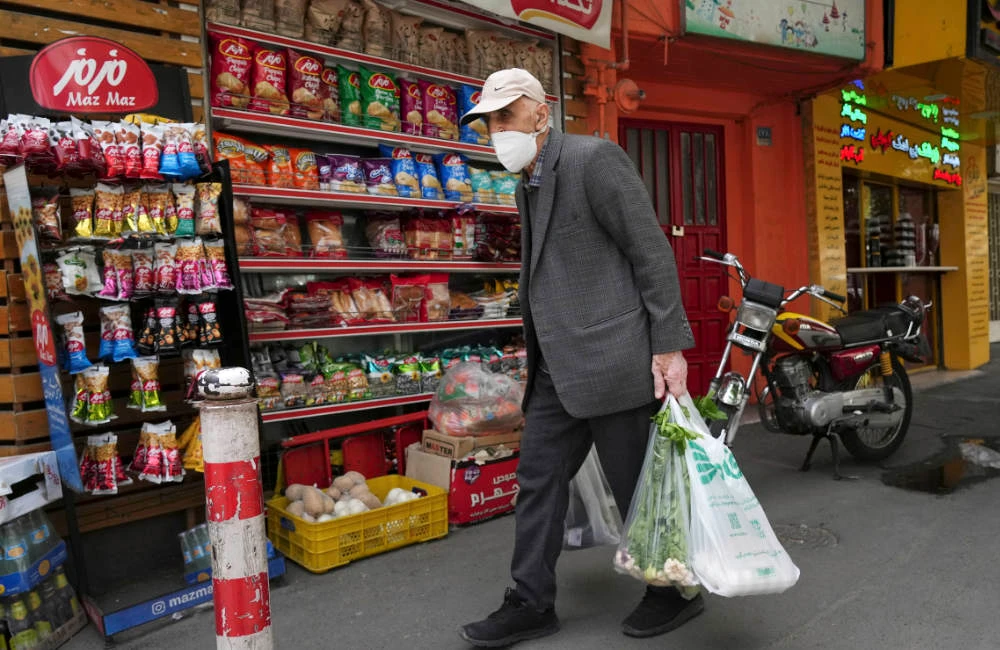 An elderly man carries his shopping in front of a grocery store in Tehran, Iran, Wednesday, May 11, 2022. (AP)