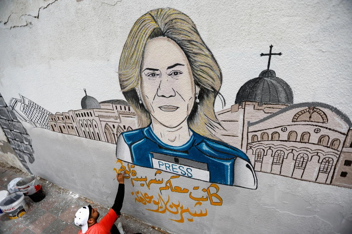 A man participates in drawing a mural of Al Jazeera reporter Shireen Abu Akleh, killed during an Israeli raid in the Israeli-occupied West Bank, in Khan Younis in the southern Gaza Strip May 14, 2022. (Reuters)