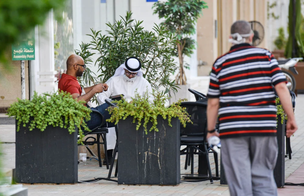 Men, one of whom is mask-clad, sit outside a cafe along Tahlia street in Riyadh. (AFP file photo)