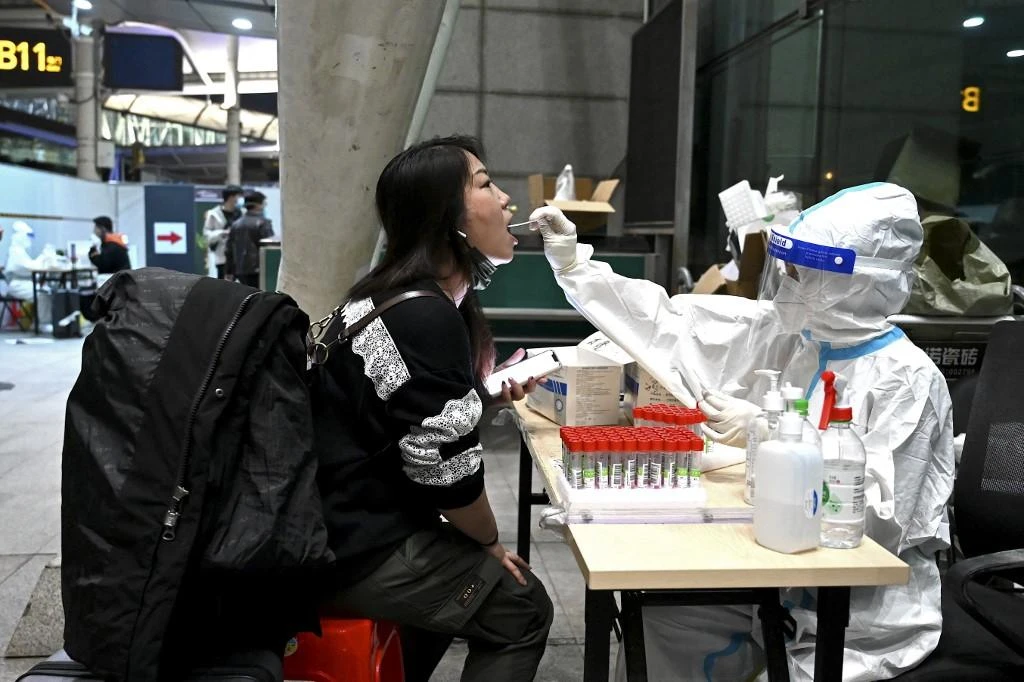 Above, a health worker gets a swab sample from an arriving passenger at the Guangzhou Baiyun International Airport in China’s southern Guangdong province on March 21, 2022. (AFP)