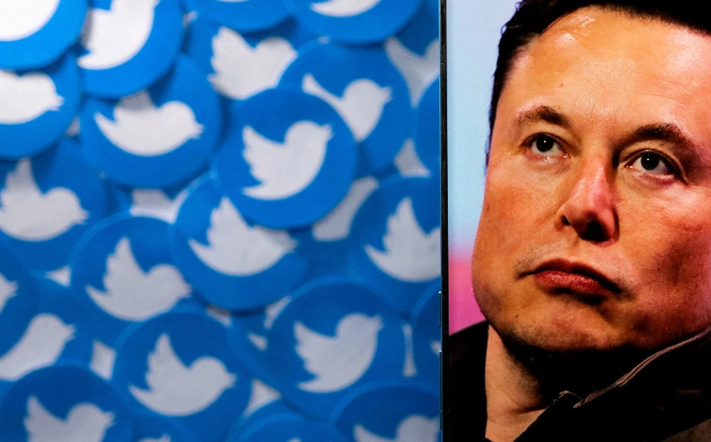 An image of Elon Musk is seen on a smartphone placed on printed Twitter logos in this picture illustration. (Reuters)