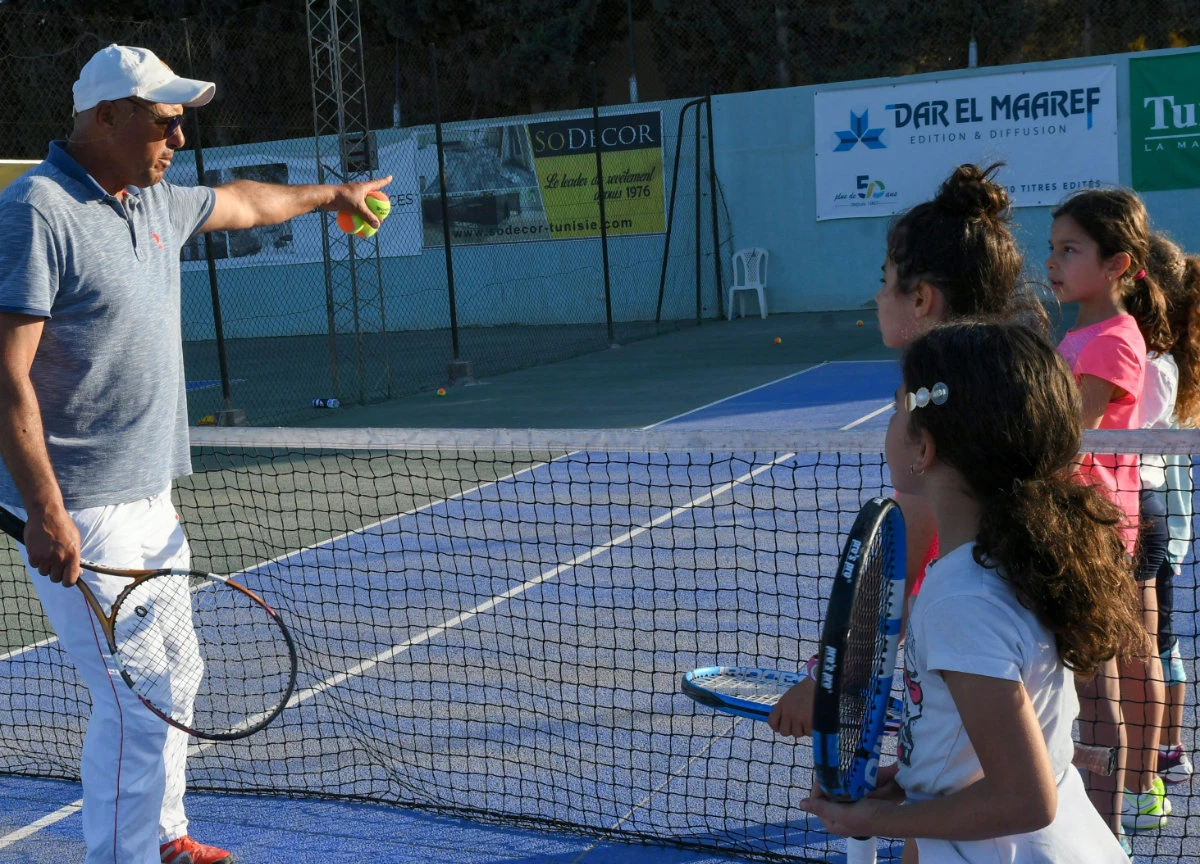 Tunisian tennis coach Nabil Mlika, who trained a young Ons Jabeur for 10 years, teaches students at the Hammam Sousse tennis club in the Mediterranean port city of Sousse on May 13, 2022. (AFP)