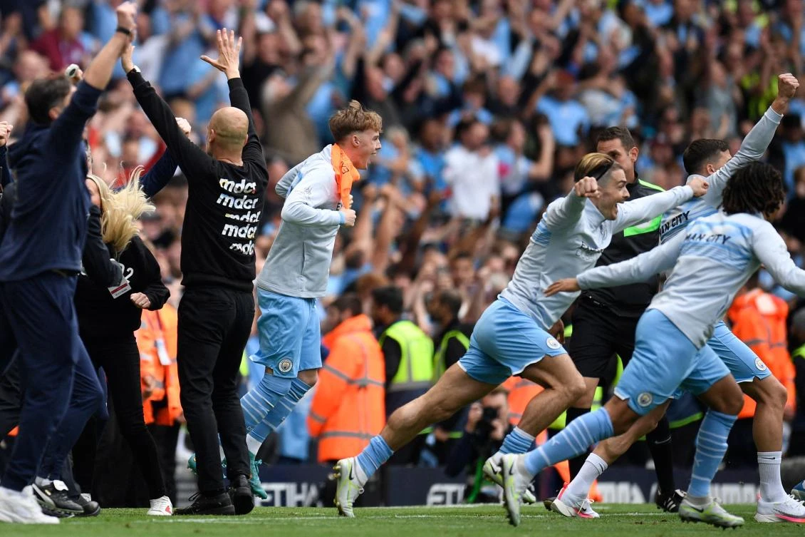 Manchester City's players run towards the pitch to celebrate after wining the English Premier League football match between Manchester City and Aston Villa in Manchester, north west England, on May 22, 2022. (AFP)