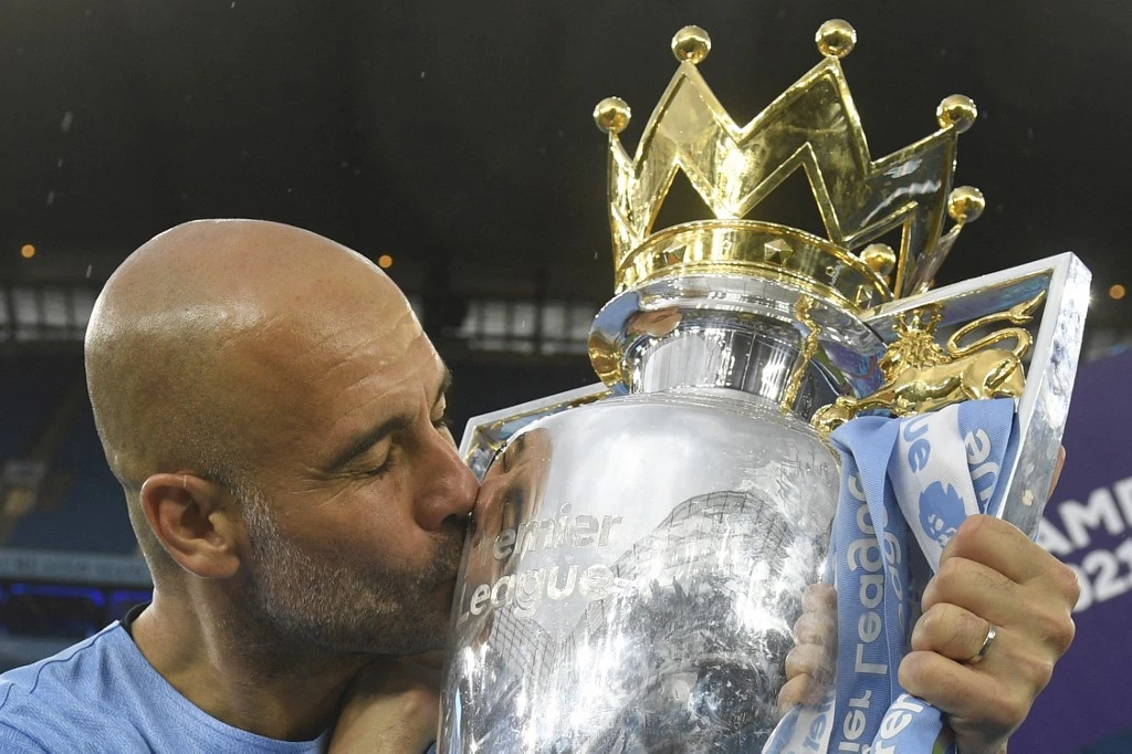 Manchester City’s manager Pep Guardiola celebrates with the Premier league trophy as the champions staged an incredible comeback from two goals down to beat Aston Villa 3-2 on Sunday. (AFP)