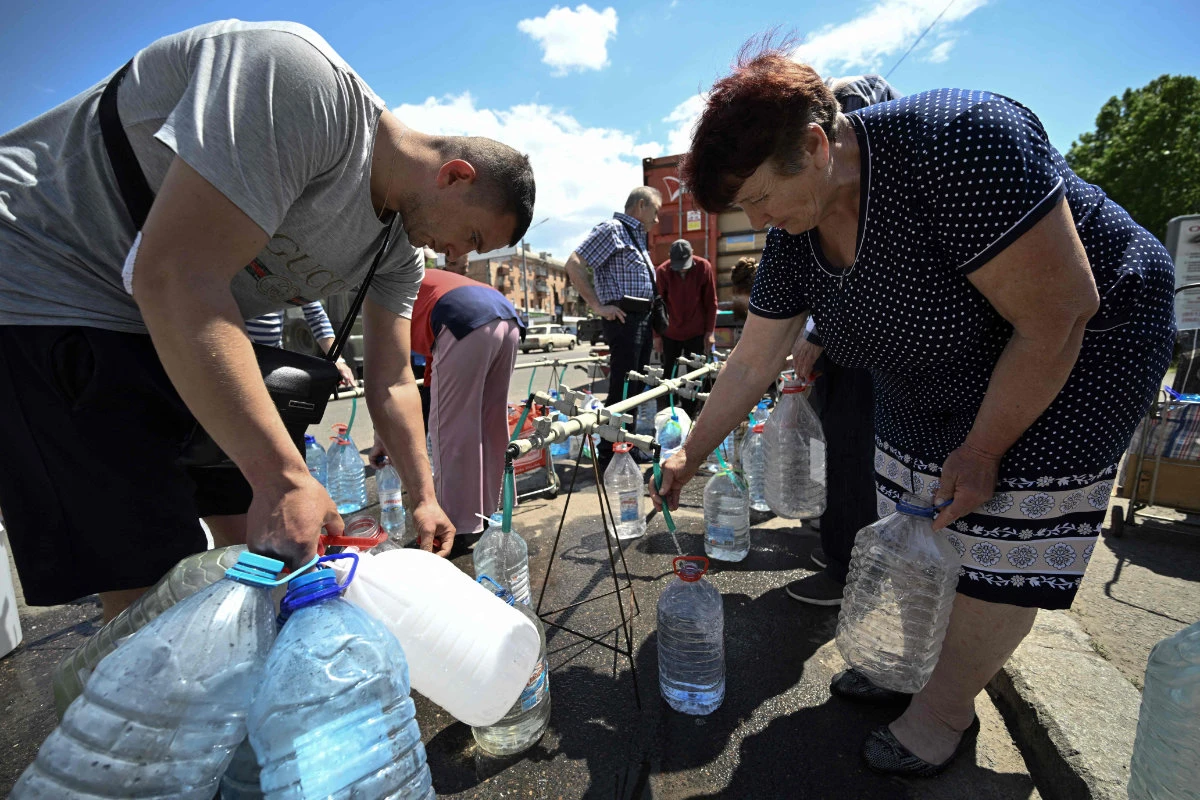 Residents collect drinking water from a supply truck in the southern Ukrainian city of Mykolaiv on May 24, 2022, amid the Russian invasion. (AFP)
