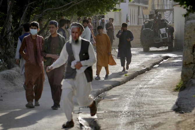 People leave the site of an explosion as a Taliban fighter stands guard in Kabul in April. On Wednesday a series of explosions shook Afghanistan, the Taliban said, including a blast inside a mosque in Kabul. (AP)