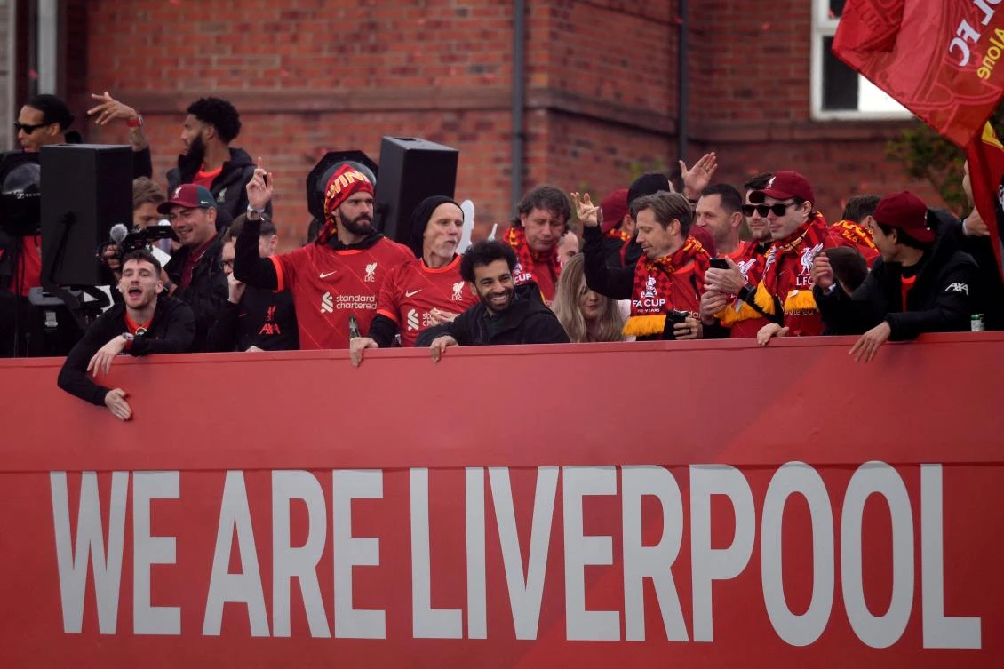 Liverpool’s Egyptian striker Mohamed Salah celebrates with teammates from an open-top bus during a parade through the streets of Liverpool on Sunday after winning the 2021-22 League Cup and FA Cup. (AFP)