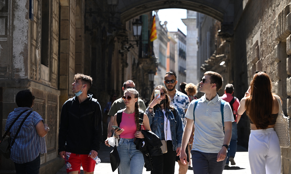 Tourists walk along the Bisbe Street in Barcelona, on May 11, 2022. (AFP)