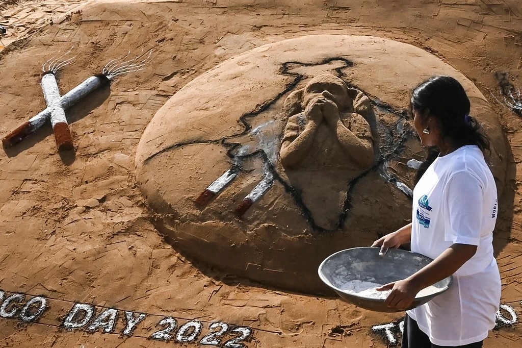Volunteers prepare a sand sculpture that was made to create awareness against the tobacco use on 'World No Tobacco' day at Elliot’s beach in Chennai on May 31, 2022. (AFP)