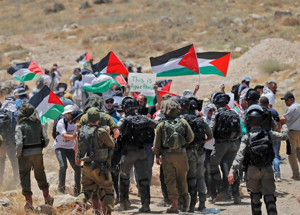 Israeli security forces surround demonstrators raising Palestinian flags, as Palestinian, left-wing, Israeli and foreign activists gather to protest against a High Court decision to evict Palestinian communities from Fire Zone 918, on June 10, 2022. (AFP)