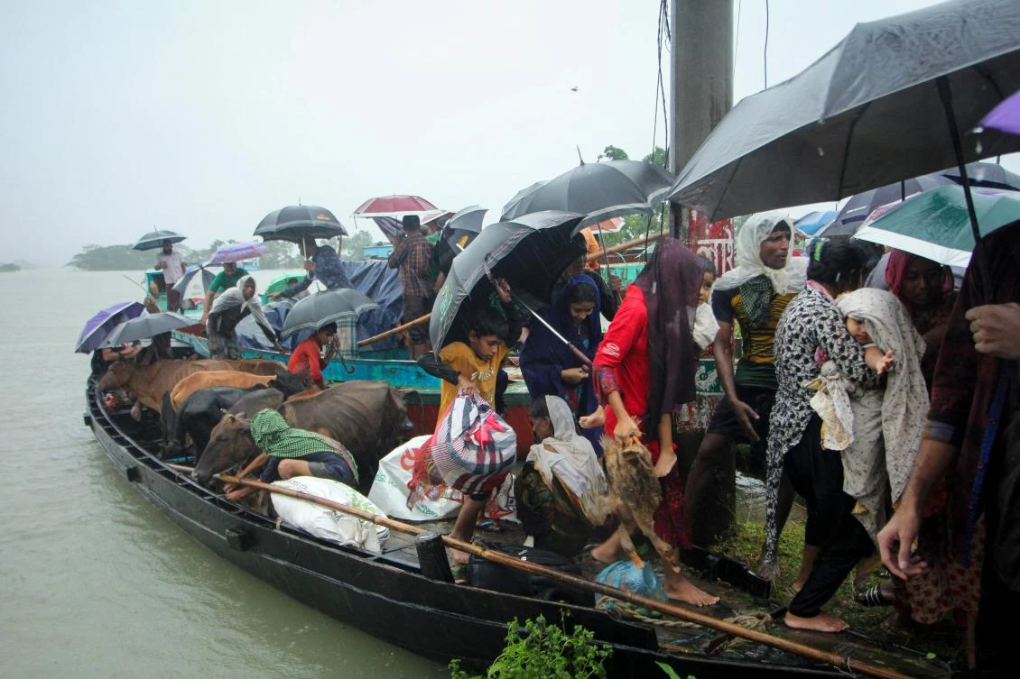 People prepare to get off a boat after being evacuated from a flooded area on the outskirts of Sylhet on June 17, 2022 (AFP)
