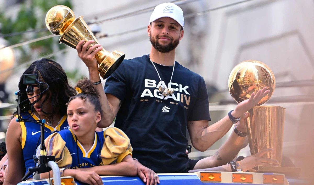 US basketball star Stephen Curry holds the MVP trophy as he waves from a double decker bus during the Golden State Warriors NBA Championship victory parade in San Francisco on June 20, 2022. (AFP)
