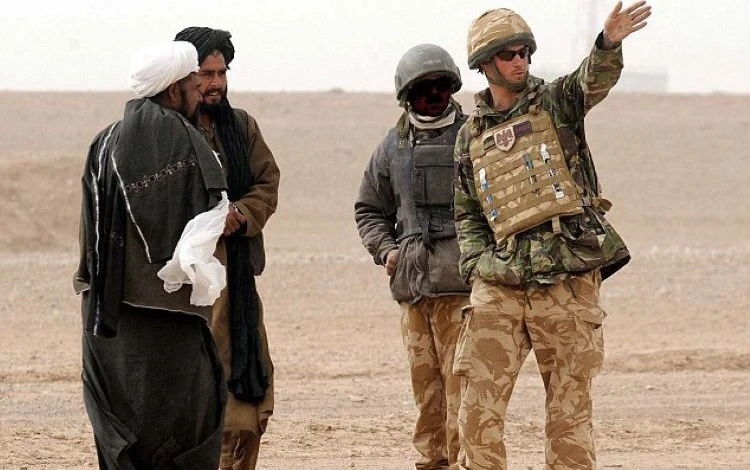 Prince Harry directs two Afghan men around a British Army cordon, with the help of an Afghan interpreter, face disguised, Helmand province, Southern Afghanistan, Feb. 21, 2008. (Reuters)