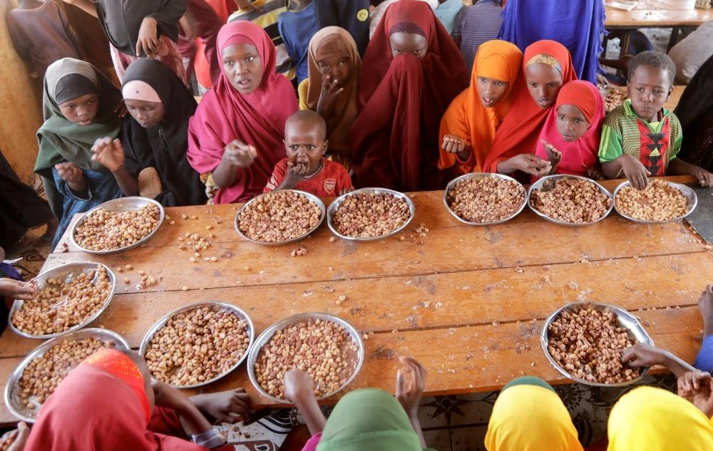Internally displaced children eat a meal at Kabasa Primary School, Dollow, Gedo Region, Somalia, May 25, 2022. (Reuters)