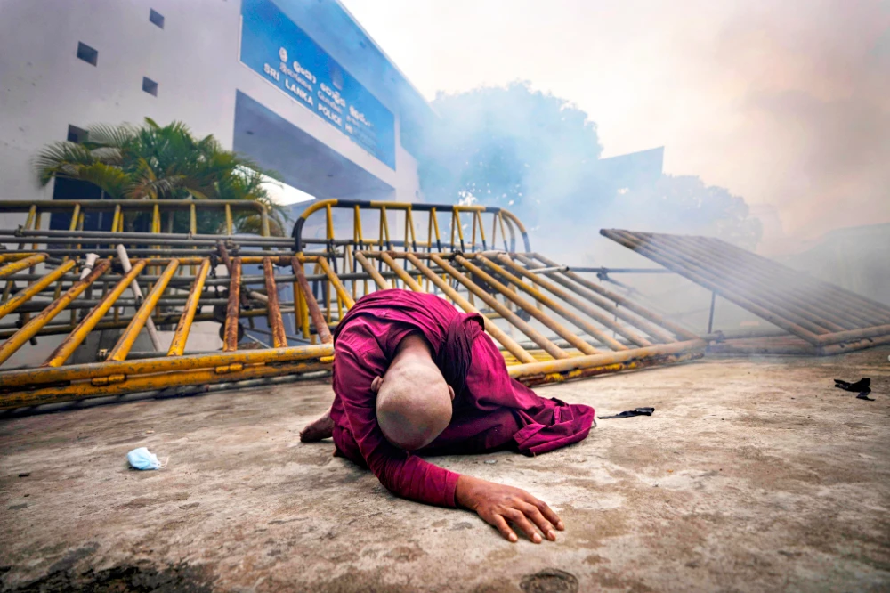 A Buddhist nun falls next to a barricade after inhaling tear gas during a protest against the economic crisis. (AP)
