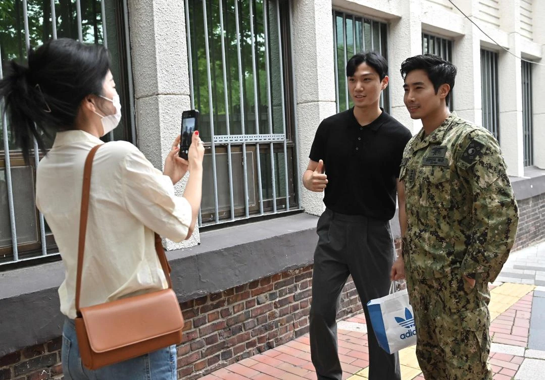 Ken Rhee, right, a former South Korean Navy special warfare officer, poses for a photo with a fan on a street in Seoul. (AFP)