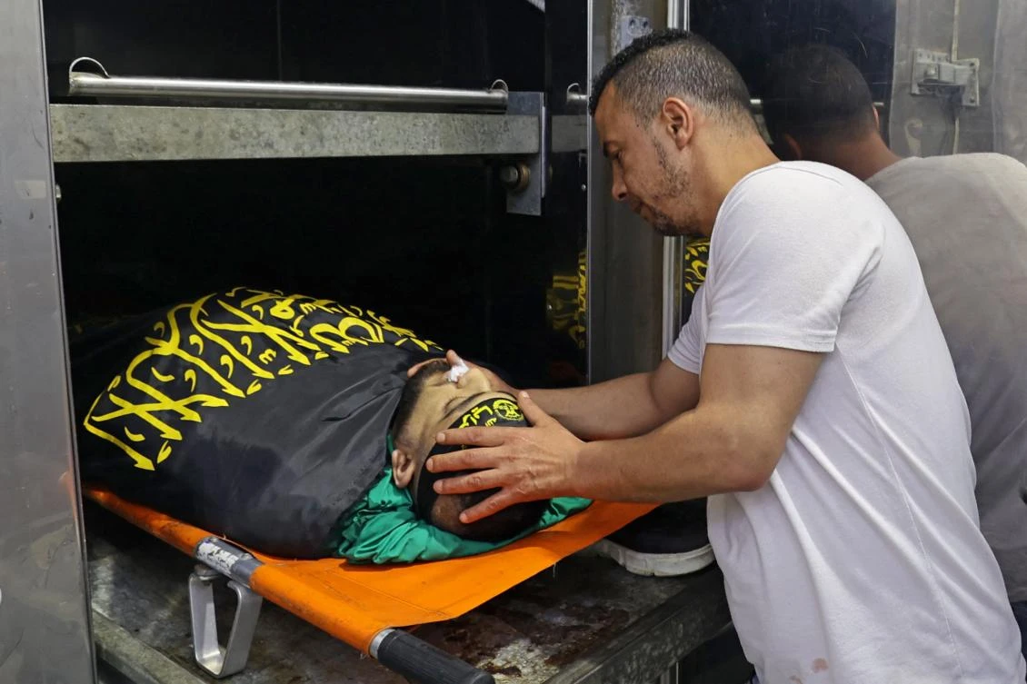 A relative checks the body of Palestinian Mohammad Marei, who was killed during an Israeli military raid in the occupied West Bank on June 29, 2022. (AFP)