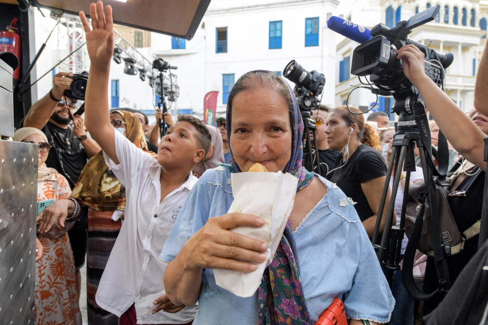 A woman prepares to eat a sandwich prepared by street food vendor Habib Hlila in Tunis. (AFP)