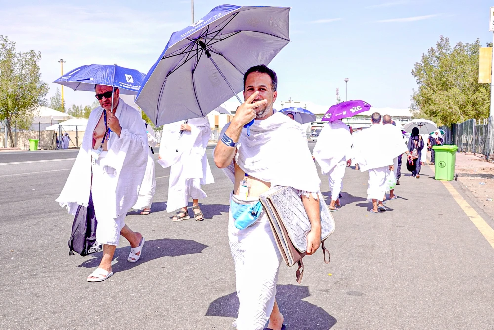 A pilgrim holding umbrella shows victory sign. (AN photo by Huda Bashatah)