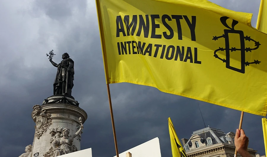 Demonstrators wave Amnesty International flag during a protest in solidarity with migrants at Place de la Republique in Paris on September 5, 2015. (AFP/FILE)