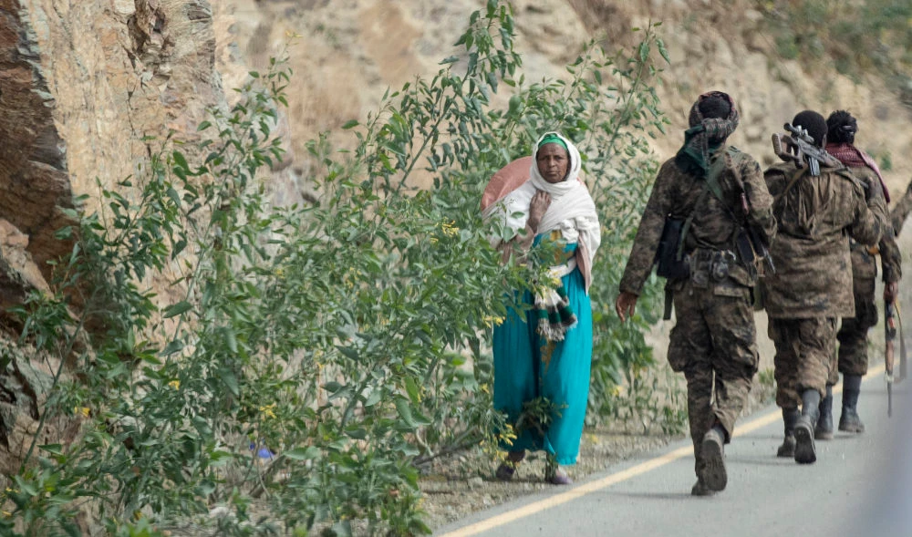 A woman walks past Ethiopian government soldiers by the side of a road north of Mekele, in the Tigray region of northern Ethiopia. (AP)