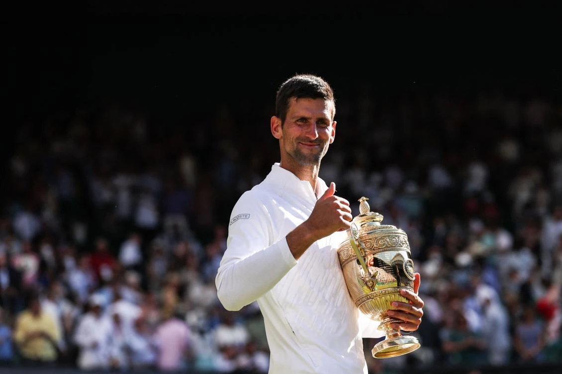 Serbia's Novak Djokovic smiles as he holds his trophy after defeating Australia's Nick Kyrgios during the men's singles final at Wimbledon. (AFP)