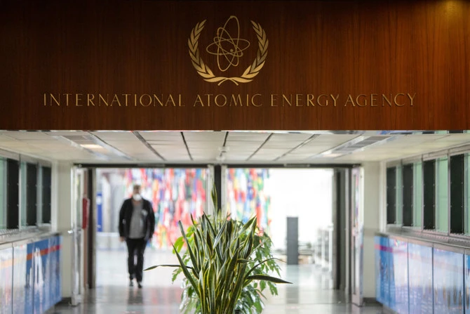 Journalist walk under the sign of the International Atomic Energy Agency at the IAEA headquarters in Vienna on May 23, 2021. (AFP)