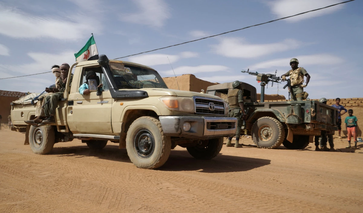 Members of The Coordination of Azawad Movements (CMA) (L) drive past a Malian military truck in a street in Menaka, Mali on May 9, 2018, during a visit of the Malian prime minister. (AFP/File)