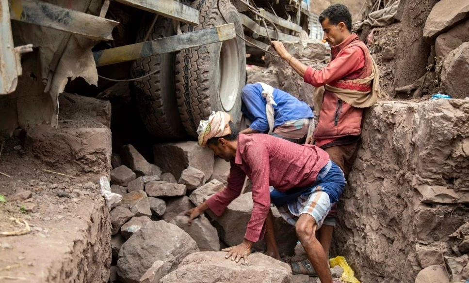 Yemenis try to move a vehicle stuck on a damaged road that serves as a lifeline between Yemen’s third-largest city of Taiz, besieged by the Houthis, and the southern port of Aden, July 8, 2022. (AFP)