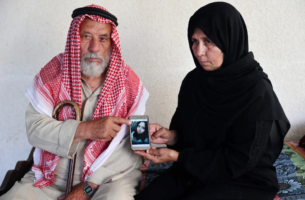 Palestinians Suleiman and Nazmiya Baraka show a picture of their slain daughter Istabraq Baraka, who was killed by her husband last year, on June 27, 2022 in their home, in Khan Yunis in the southern Gaza Strip. (AFP)