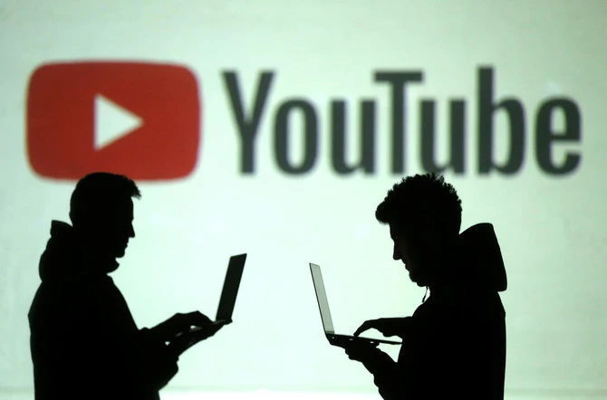 Silhouettes of users are seen next to a screen projection of the Youtube logo in this picture illustration taken March 28, 2018. (REUTERS/FILE)