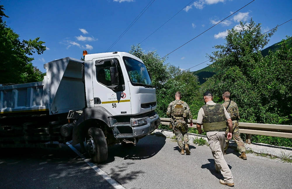 US NATO soldiers serving in Kosovo patrol next to a road barricade set up by ethnic Serbs near the town of Zubin Potok on August 1, 2022. (AFP)