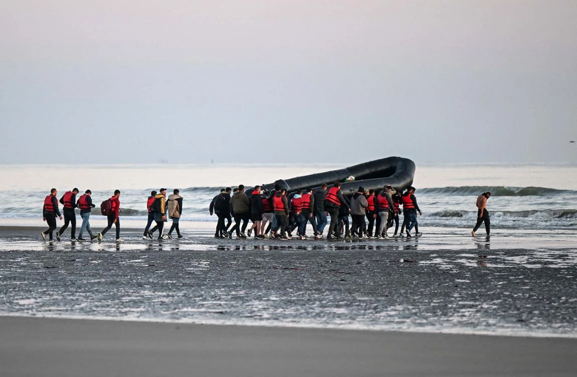 This file photo taken on July 11, about 40 migrants carry an inflatable boat toward the water before they attempt to cross the Channel illegally to Britain, near the northern French city of Gravelines. (AFP/File)