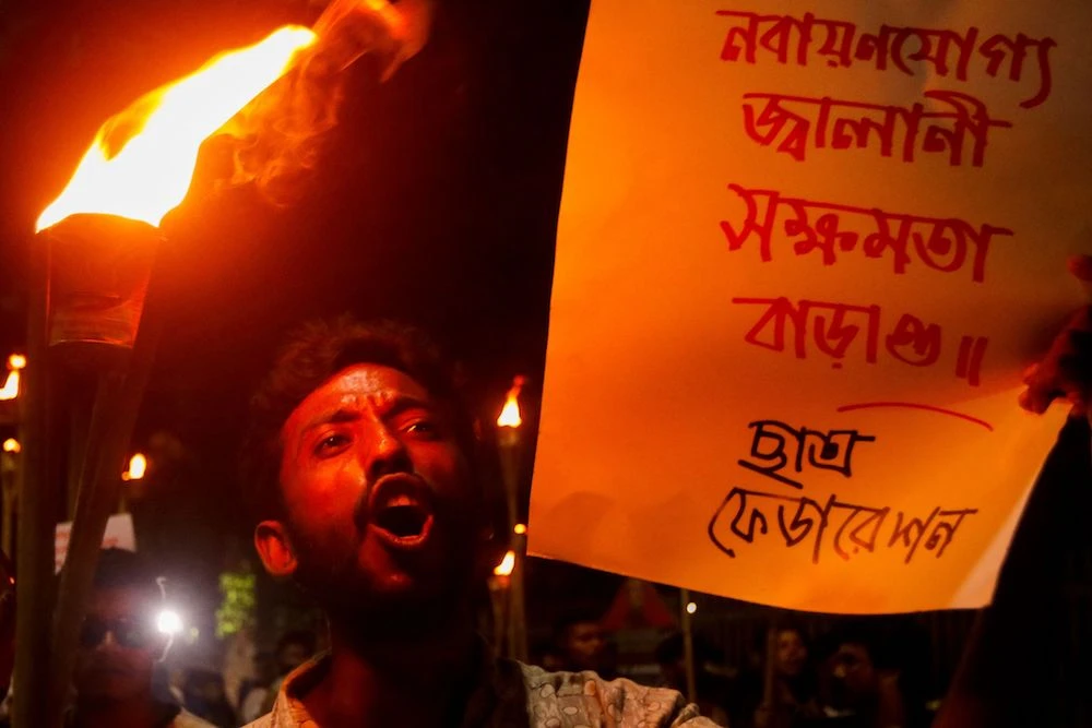 An activist displays a banner and shout slogans during a torch rally to protest against rising fuel prices in Dhaka on August 6, 2022. (AFP)