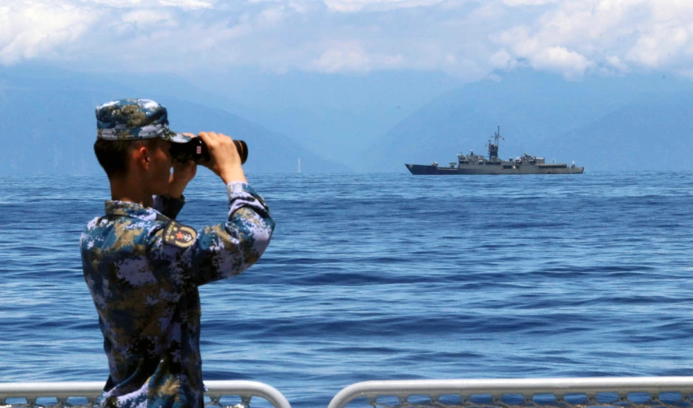 A People's Liberation Army member looks through binoculars during military exercises as Taiwan’s frigate Lan Yang is seen at the rear, on Friday, Aug. 5, 2022. (AP)