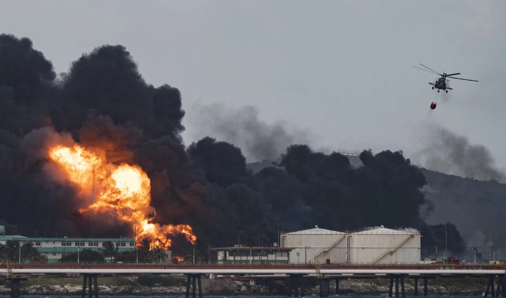 A firefighter helicopter drops water on a massive fire at a fuel depot in Matanzas, Cuba, on August 8, 2022 (AFP)