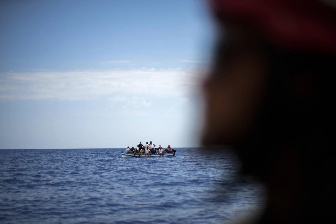 Migrants from Tunisia wait in a wooden boat as they are assisted by Spanish NGO Open Arms crew members during a rescue operation, south of the Italian Lampedusa island at the Mediterranean sea, Saturday, Aug. 6, 2022. (AP)
