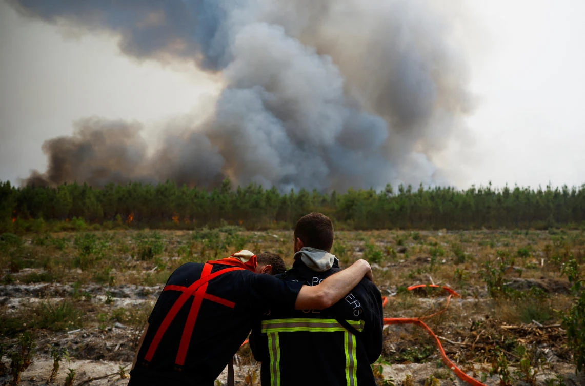 Firefighters embrace as they work to contain a fire in Saint-Magne, as wildfires continue to spread in the Gironde region of southwestern France, on Thursday. (Reuters)