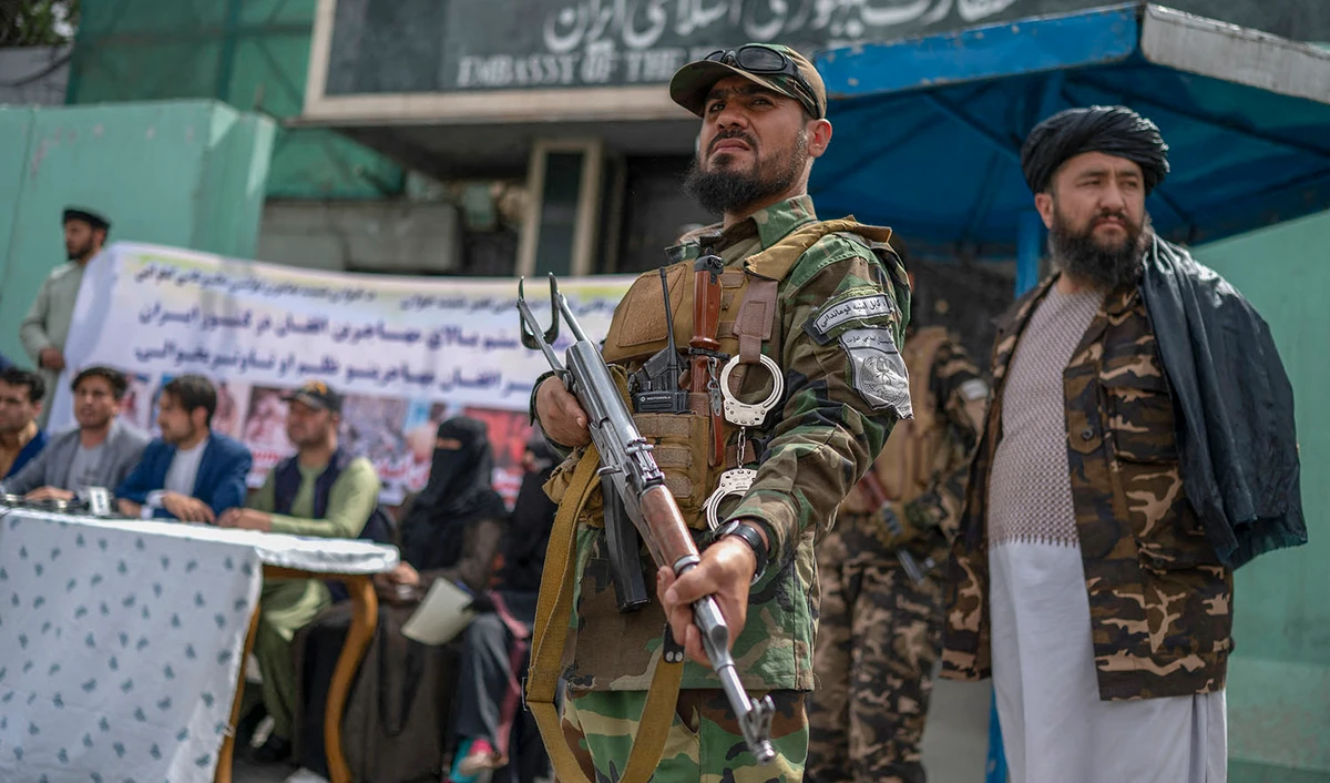 Taliban fighters stand guard as Afghan protestors take part in a protest against the alleged published reports of harassment of Afghan refugees in Iran, in front of the Iranian embassy in Kabul on April 11, 2022. (AFP/File)