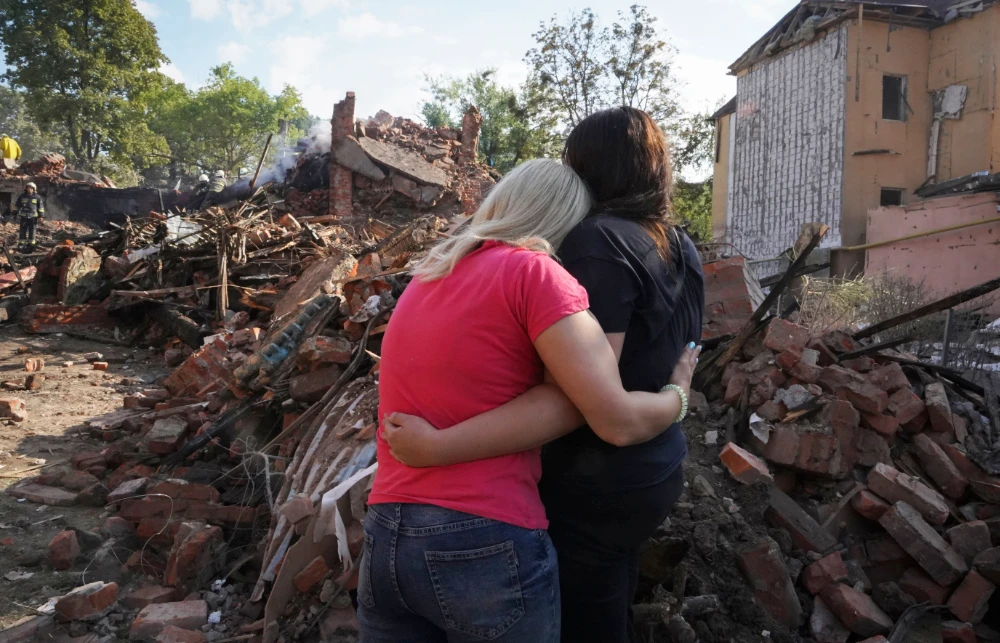 Ukrainian women hug in front of a building destroyed during a missile strike in Kharkiv, Ukraine. (AP)