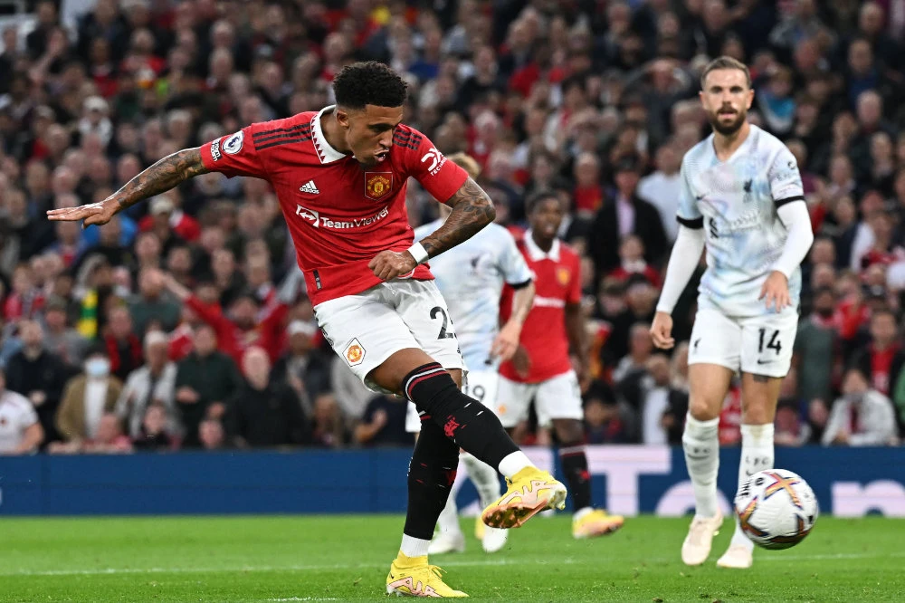 Manchester United’s English striker Jadon Sancho (L) shoots to score the opening goal during the English Premier League football match between Manchester United and Liverpool at Old Trafford in Manchester on August 22, 2022. (AFP)